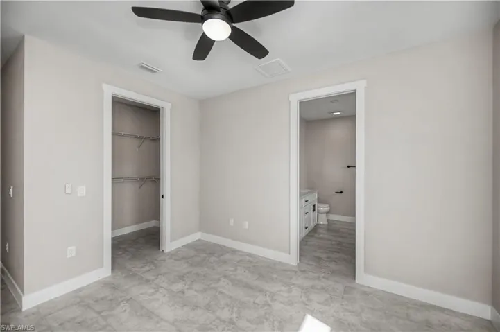 Unfurnished bedroom featuring a spacious closet and a ceiling fan