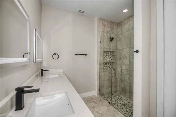 Full bathroom featuring a stall shower, double vanity, and recessed lighting