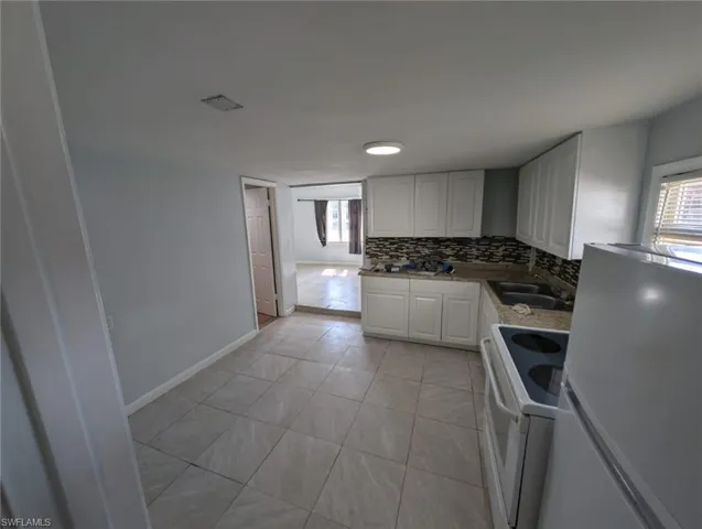 Kitchen with white cabinets, sink, white appliances, and decorative backsplash