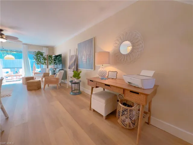 Home office featuring ornamental molding, light wood-type flooring, a ceiling fan, and a wall of windows