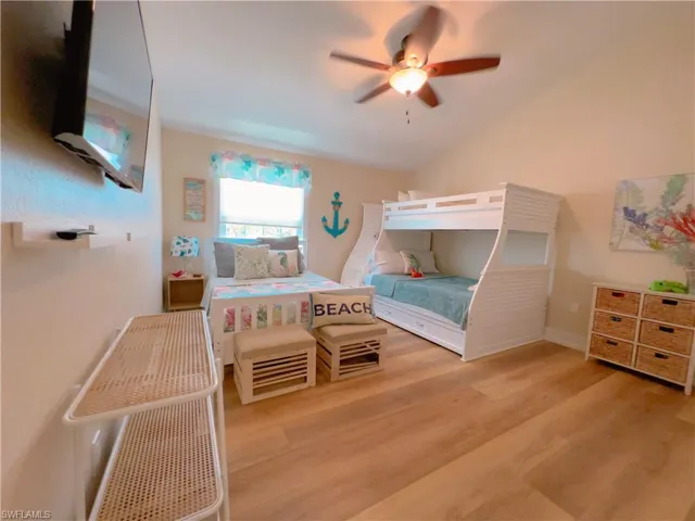 Bedroom with light wood finished floors, a ceiling fan, and lofted ceiling