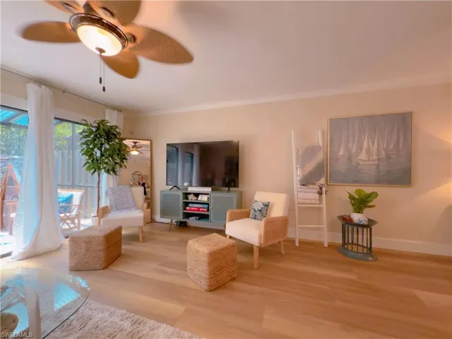 Living room with light wood-style flooring, ceiling fan, and crown molding