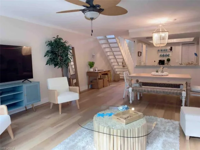 Living area featuring wood finished floors, a ceiling fan, and stairs