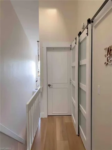 Corridor featuring a barn door and light wood-style flooring