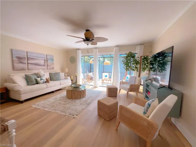 Living room featuring light wood-style flooring, crown molding, and ceiling fan