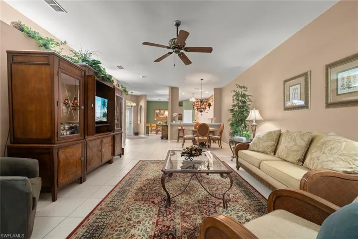 Living area featuring neutral ceramic tile flooring, a central ceiling fan, and a pass-through opening to the dining area