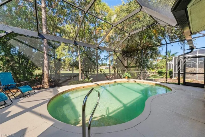 Screen-enclosed pool area featuring a picture screen, and mature landscaping