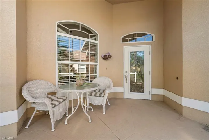Covered porch featuring stucco exterior walls, a white-framed glass-paneled door with an arched window with a transom