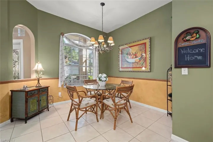 Dining area featuring neutral tile flooring, two-tone wall finish with wainscoting, and a multi-arm chandelier