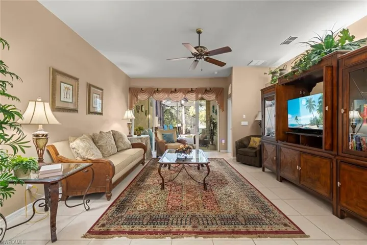 Living area featuring neutral wall tones, large-format tile flooring, a ceiling fan, and sliding glass doors