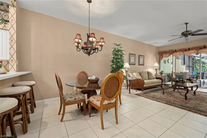 Open-concept main living area featuring ceramic tile flooring, a multi-arm iron chandelier, and a ceiling fan with integrated lighting