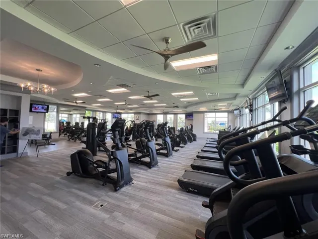 Gym with a raised ceiling, a ceiling fan, and a drop ceiling