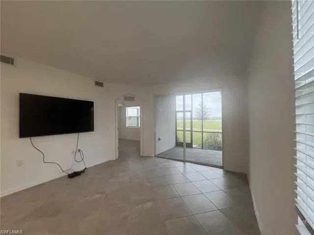 Unfurnished living room with arched walkways and light tile patterned floors