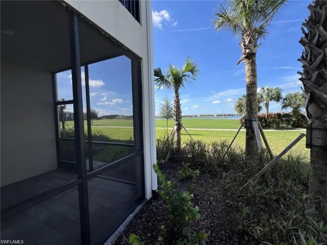 View of green lawn featuring view of golf course and a sunroom