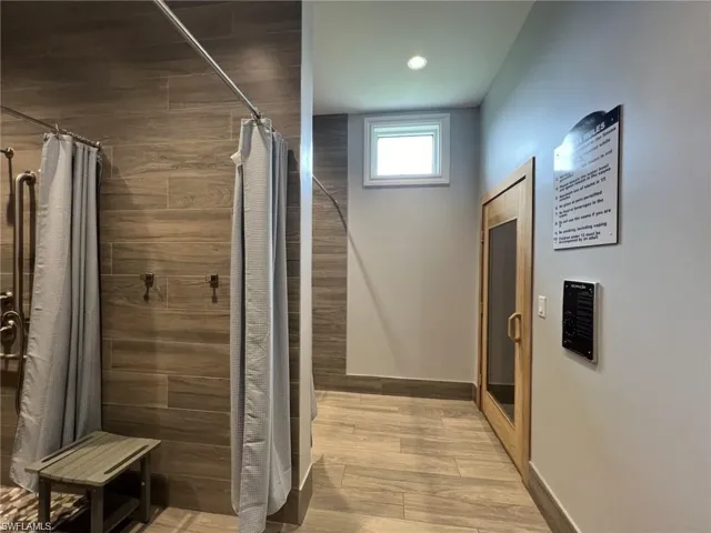Locker room featuring a shower stall, sauna, light wood finished floors, and recessed lighting