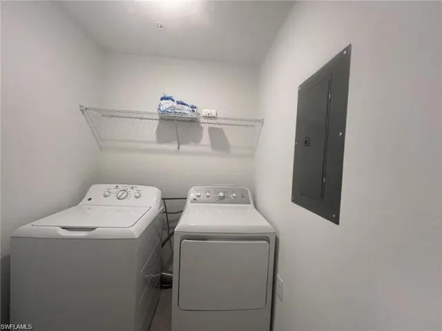 Laundry area featuring electric panel and washing machine and dryer