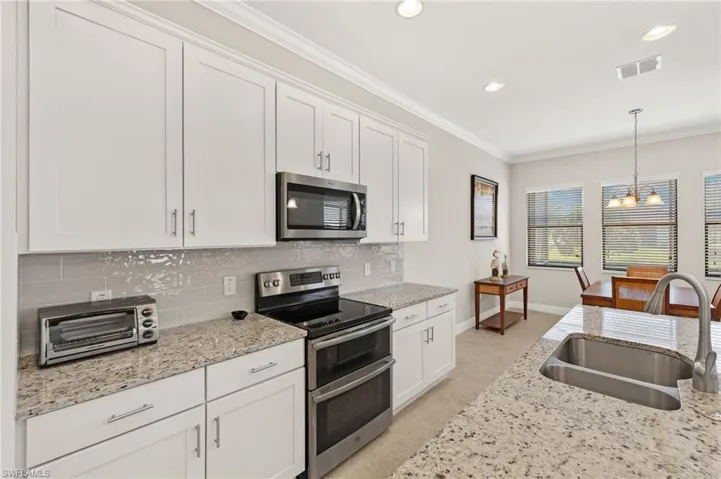 Kitchen with stainless steel appliances, visible vents, a sink, tasteful backsplash, and a notable chandelier