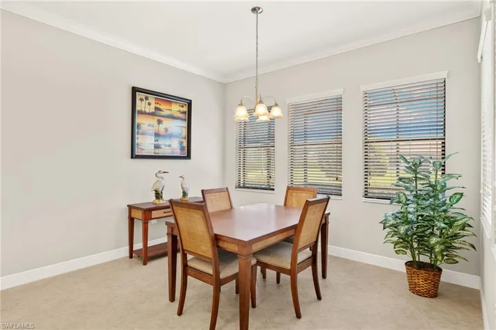 Dining space with baseboards, an inviting chandelier, ornamental molding, and a healthy amount of sunlight