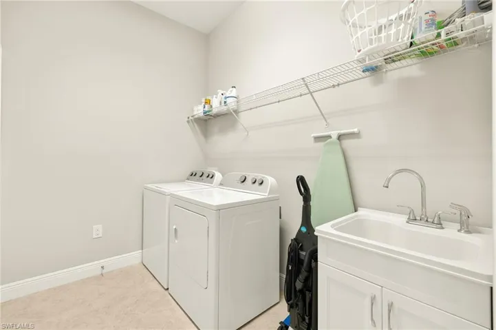 Washroom featuring separate washer and dryer, baseboards, cabinet space, and a sink