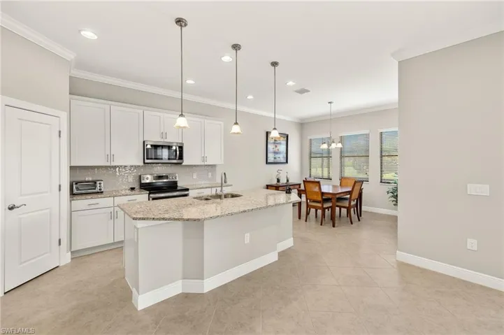 Kitchen with stainless steel appliances, backsplash, a sink, crown molding, and a chandelier