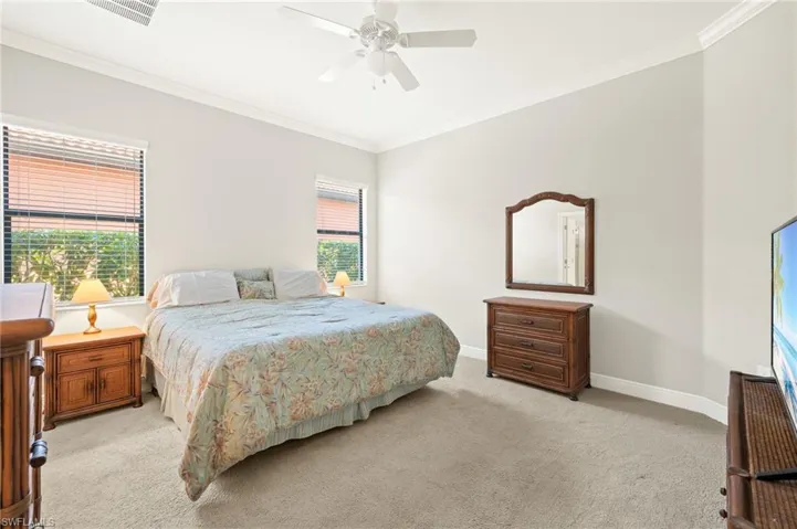 Bedroom featuring ceiling fan, light carpet, baseboards, ornamental molding, and visible vents