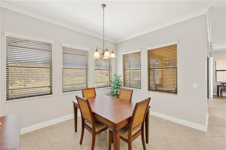 Dining space featuring baseboards, a chandelier, ornamental molding, and light tile patterned flooring