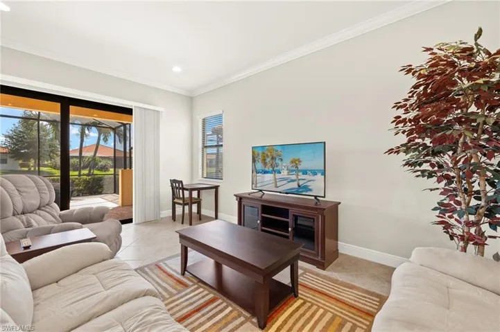 Living room with a wealth of natural light, baseboards, and ornamental molding