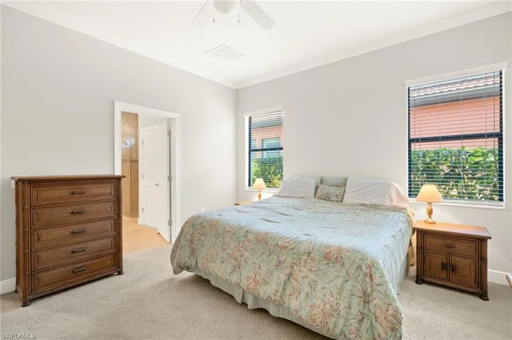 Bedroom featuring ceiling fan, baseboards, light colored carpet, and ornamental molding