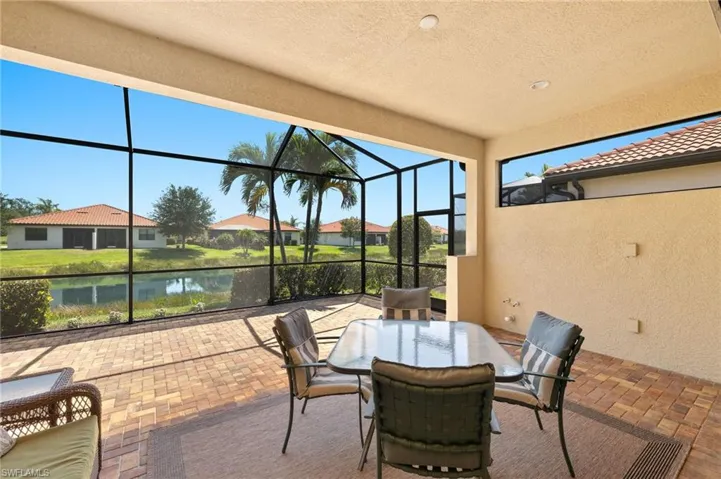 View of patio featuring glass enclosure, a residential view, and a water view