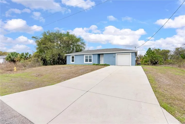 Single story home with a front lawn, concrete driveway, an attached garage, and stucco siding