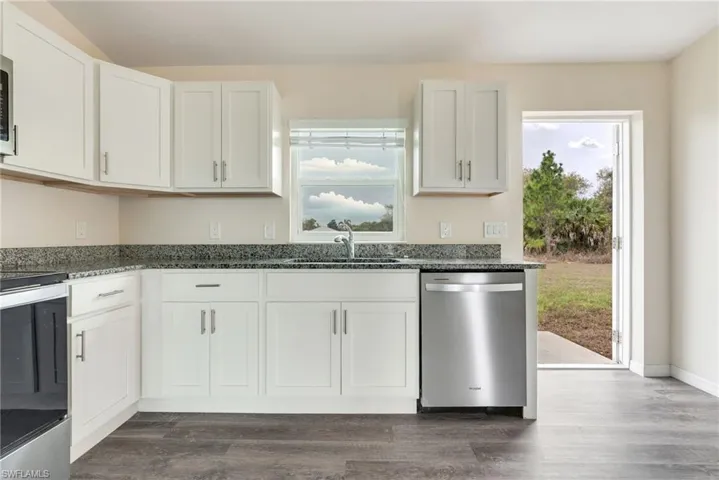 Kitchen with stainless steel appliances, dark stone countertops, and white cabinets