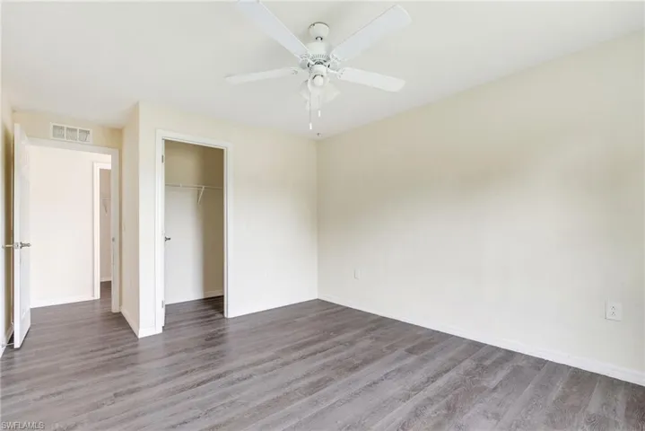 Unfurnished bedroom featuring dark wood-type flooring, ceiling fan, and a closet