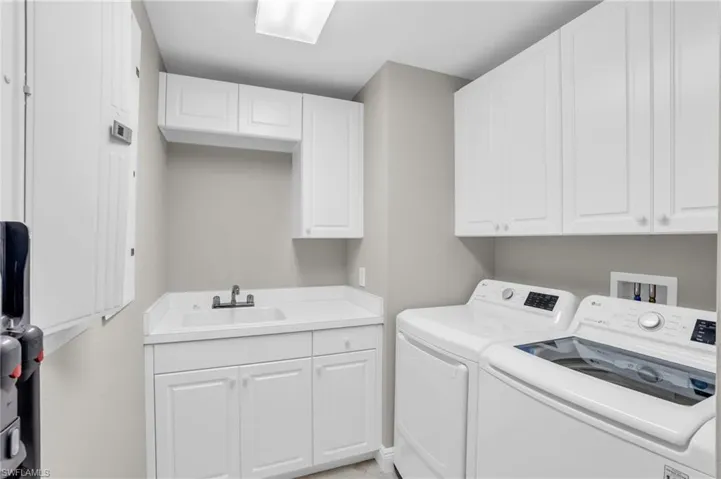 Laundry room with hookup for a washing machine, sink, separate washer and dryer, and cabinets