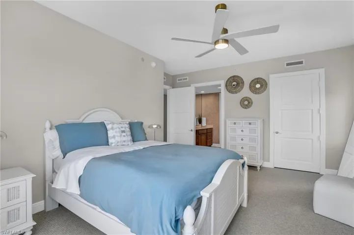 Carpeted bedroom with ensuite bathroom and ceiling fan
