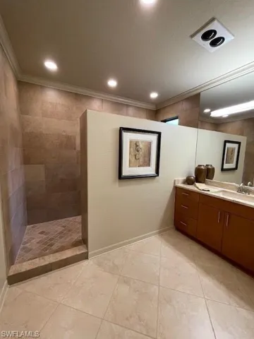 Bathroom featuring tile flooring, tiled shower, a textured ceiling, ornamental molding, and vanity