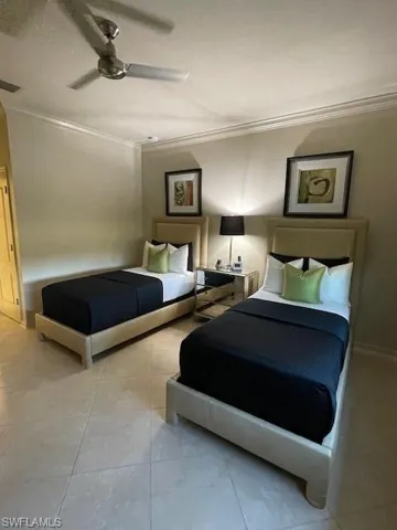 Tiled bedroom with ceiling fan and crown molding
