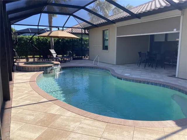 View of swimming pool featuring a patio, pool water feature, and glass enclosure