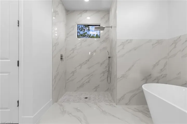 Bathroom featuring shower with separate bathtub, tile flooring, and tile walls