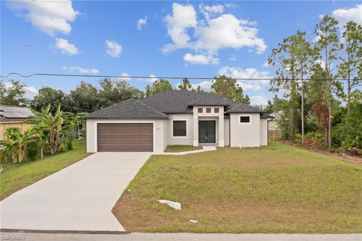 View of front of home featuring a garage, a front yard, and solar panels