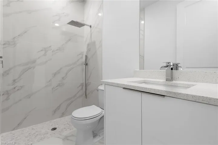 Bathroom featuring tiled shower, vanity, and toilet