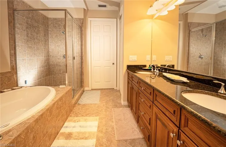 Full bath featuring double vanity, a garden tub, a shower stall, and light tile patterned floors