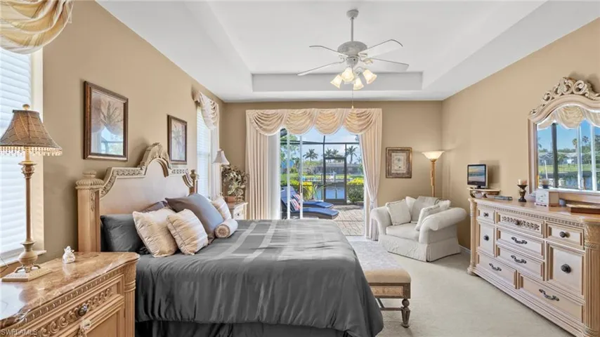 Bedroom featuring access to outside, multiple windows, ceiling fan, and a raised ceiling