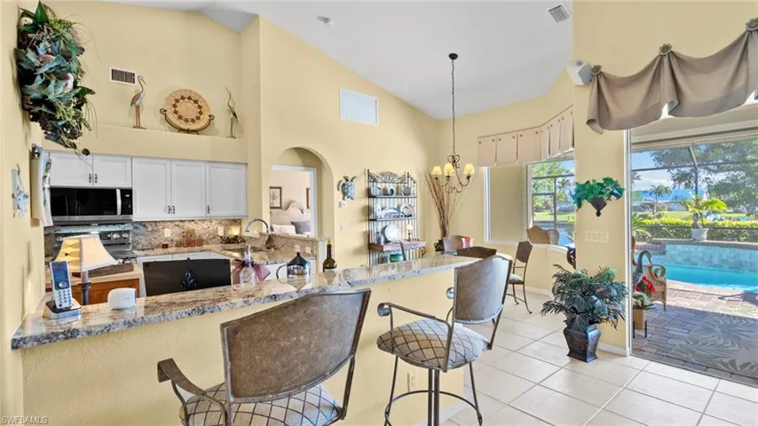 Kitchen with kitchen peninsula, a notable chandelier, white cabinetry, hanging light fixtures, and light tile patterned flooring