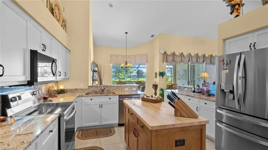 Kitchen with white cabinetry, sink, stainless steel appliances, a chandelier, and pendant lighting