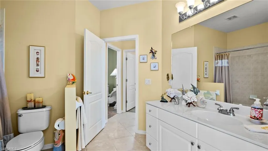 Bathroom with toilet, a shower with curtain, vanity, and tile patterned floors
