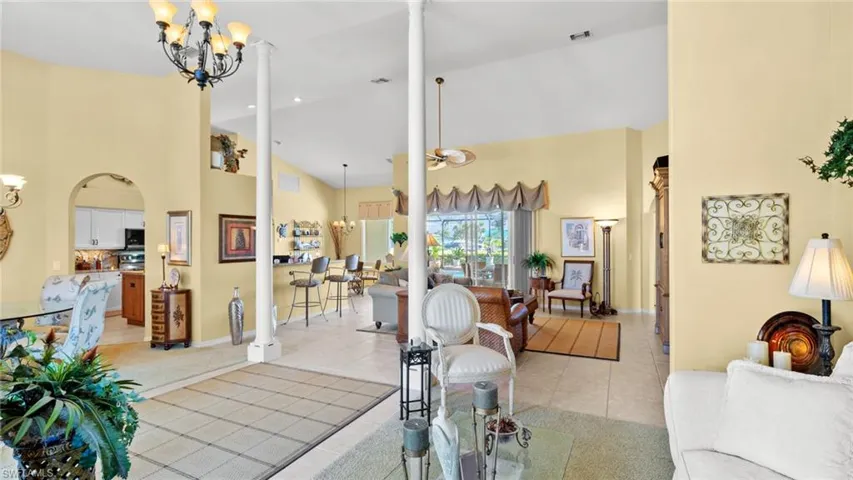 Living room with light tile patterned floors, high vaulted ceiling, and a notable chandelier