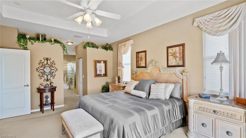 Carpeted bedroom with ceiling fan and a tray ceiling