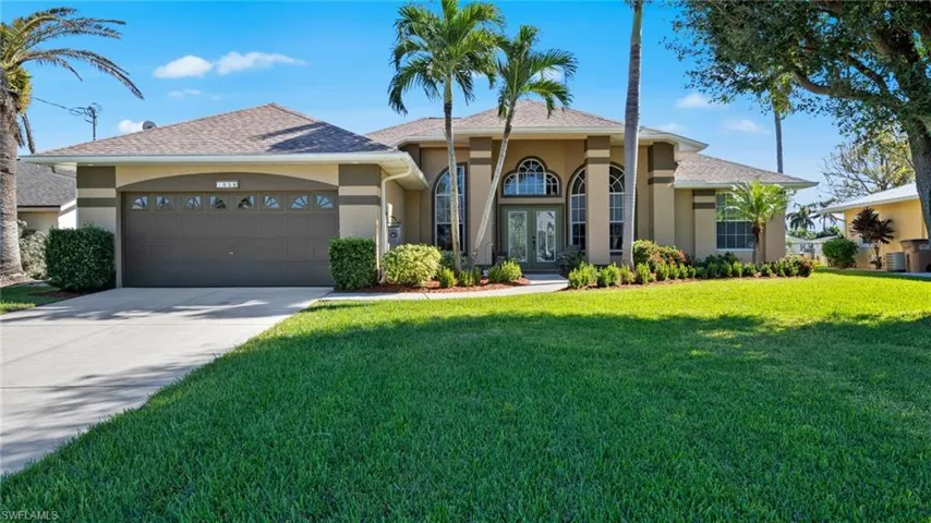 View of front of house with central AC, a garage, and a front lawn