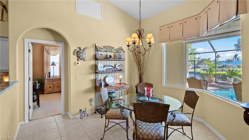 Dining room featuring light tile patterned floors, lofted ceiling, a wealth of natural light, and a notable chandelier