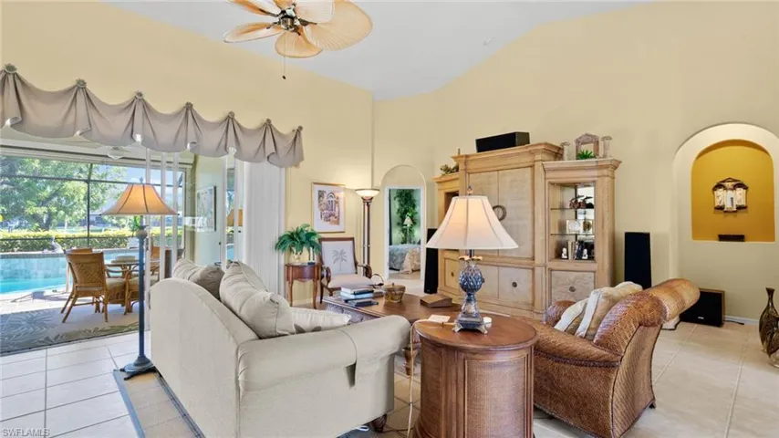 Living room featuring ceiling fan, light tile patterned floors, and vaulted ceiling